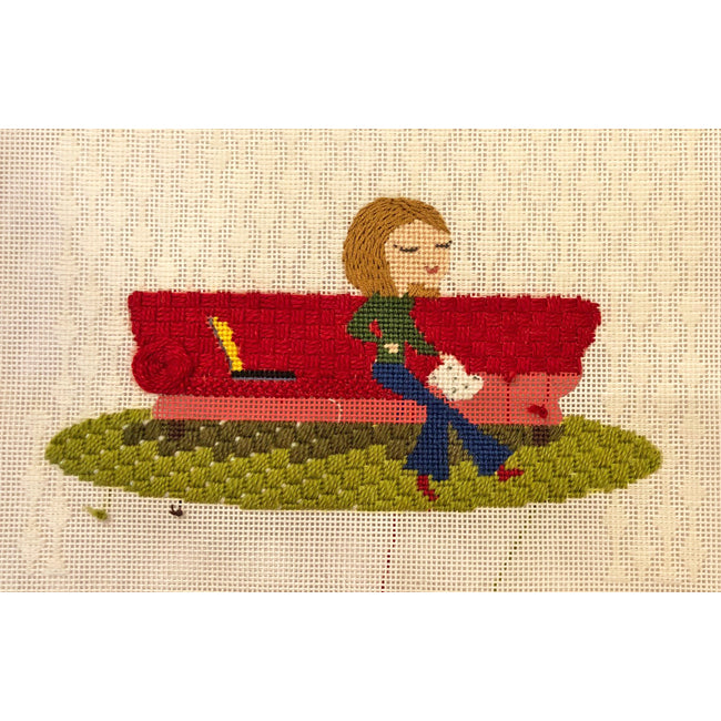 Needlepoint-for-fun stitcher on red sofa
